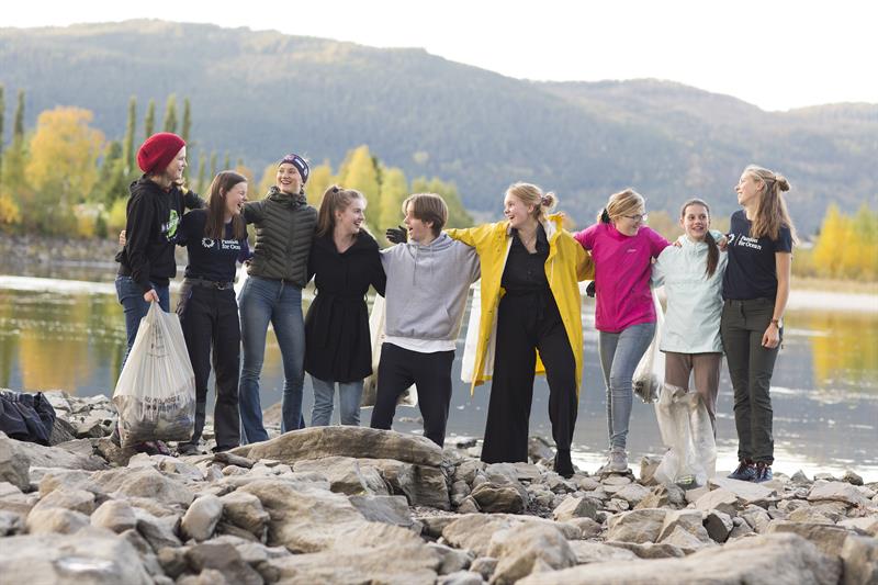 Ni ungdommer står foran elva Orkla og holder rundt hverandre. De var med «Passion for Ocean» på plastrydding. Foto: Ronny Danielsen.