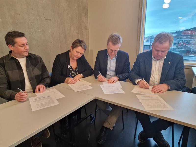 Signering-regional-samarbeidsavtale-2.jpg Fire personer ved et bord signerer regional samarbeidsavtale for næringsutvikling.
