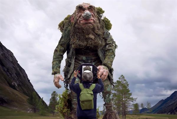 En gutt står med trolldetektor foran et troll i naturen. Foto: iTrollheimen.