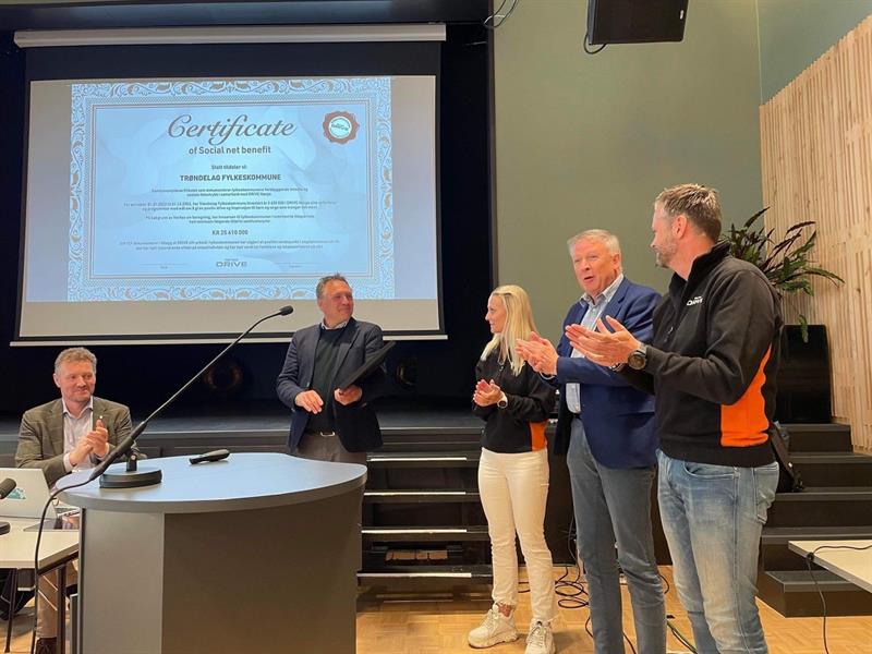 Fylkesordfører Tore O. Sandvik mottar det synlige beviset på fylkeskommunens tilførte samfunnsbidrag fra DRIVE. Foto: DRIVE Norge. 