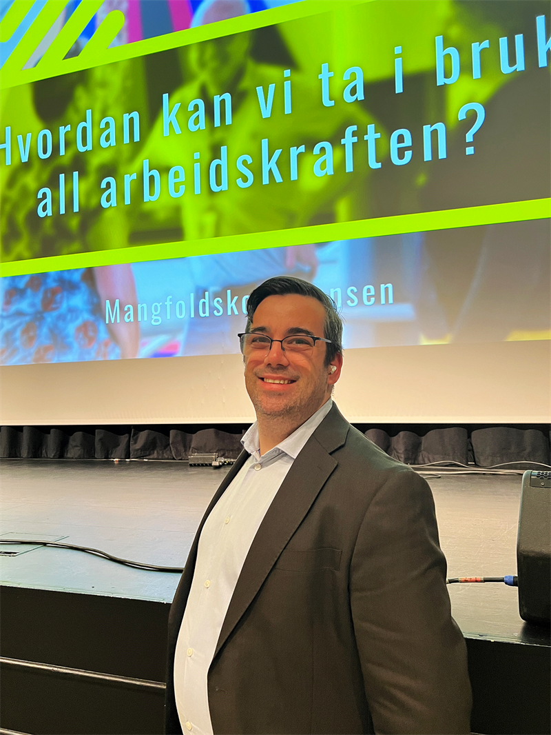 Daglig leder i InClue (Handicapforbundets rekrutterings- og kompetansehus), Tor Andreas Bremnes står foran scenen. I bakgrunnen står det "Hvordan kan vi ta i bruk all arbeidskraften?"