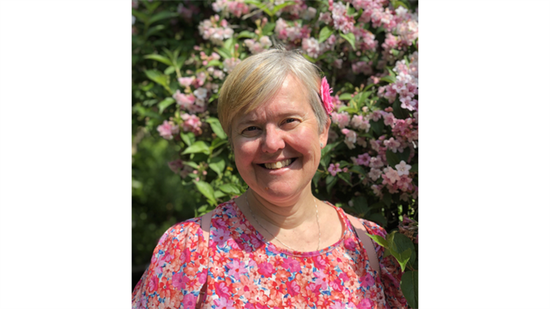 Bilde av dame foran blomster. Ny rektor.
