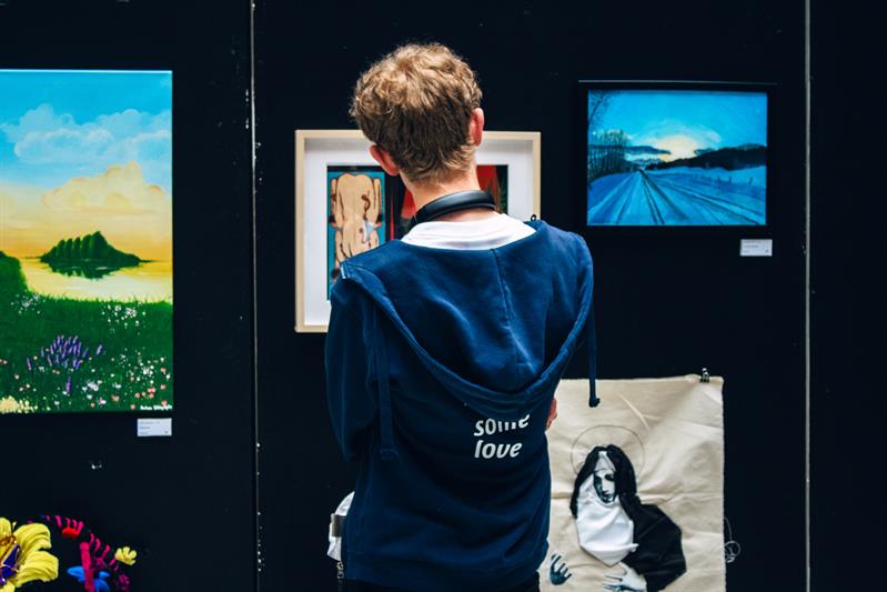 Kunstnerkaffe-Ylva Sturød-8671.jpg Person som står foran ulike kunstverk.