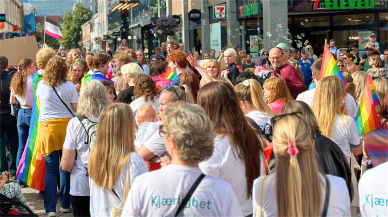 Folkemengde og pride-flagg under pride-tog i Trondheim sentrum.