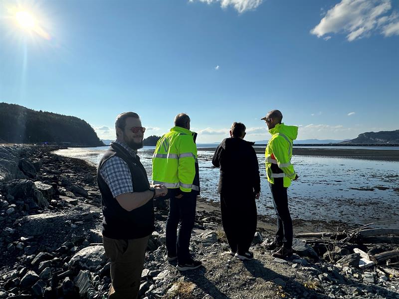 Hovedutvalgsleder Jonas Ali Ghanizadeh ser mot kamera, og i bakgrunnen skuer Nye veier og ordføreren i Stjørdal utover Trondheimsfjorden fra Hellstranda.