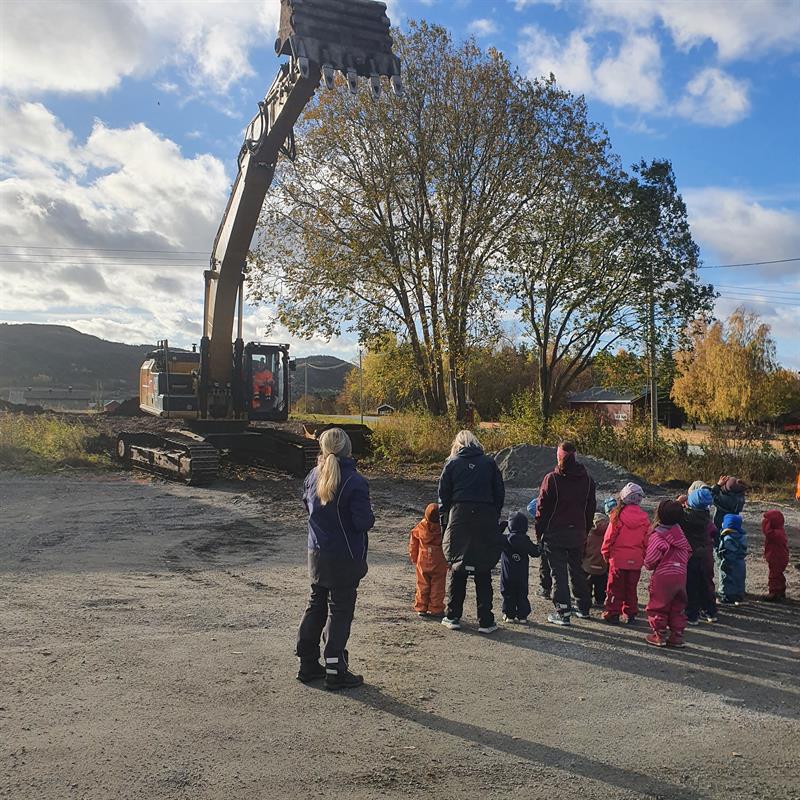 Bilde av gravemaskin og barnehagebarn.