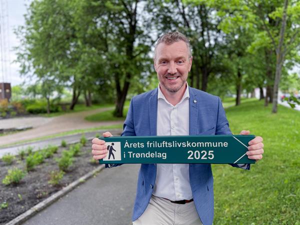 Bilde av fylkesordfører Tomas Iver Hallem som holder et turskilt som det står Årets friluftskommune 2025
