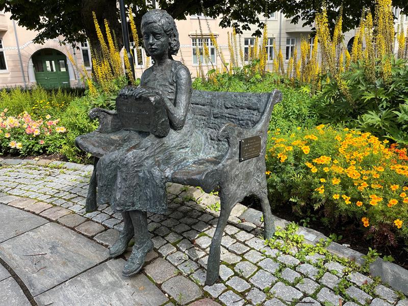 Statue av Cissi Klein som sitter på en benk. 