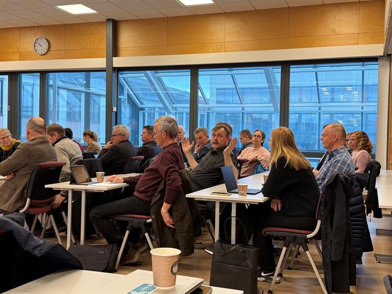 Ordførere og kommunedirektører fra sitter i rekker ved siden av hverandre i Fylkestingssalen.