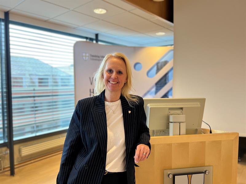 Ingvill Dalseg, leder for hovedutvalg næring og industri i Trøndelag fylkeskommune, står foran en talerstol og smiler til kamera.
