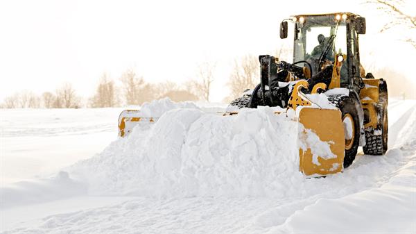 Hjullaster som brøyter bort snø. Bilde
