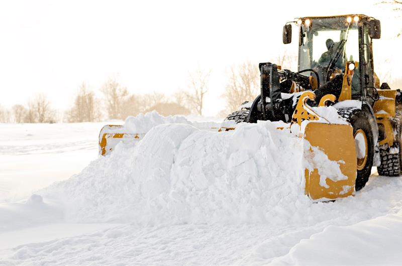 Hjullaster som brøyter bort snø. Bilde