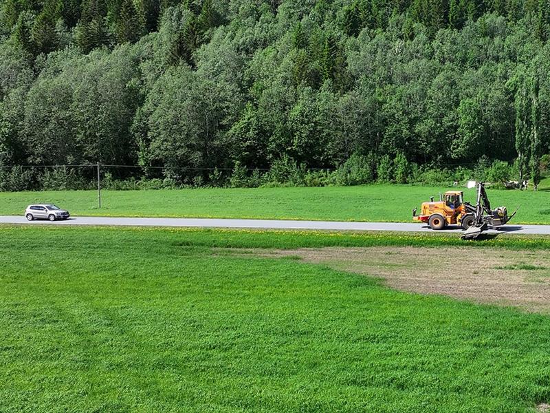 Kantslåttmaskin i drift langs veg. Bilde