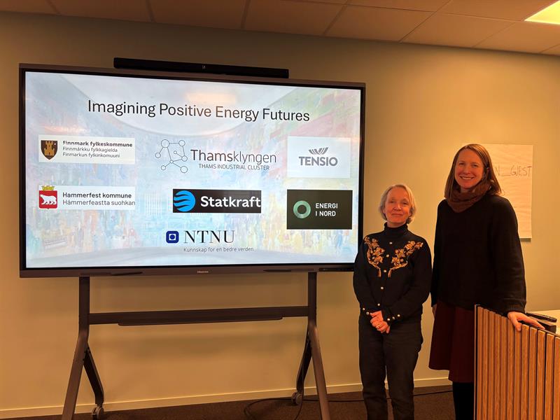 To kvinner står ved et lerret og presenterer for publikum.